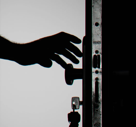Silhouette of a hand about to open a door with keys in lock, symbolizing security.